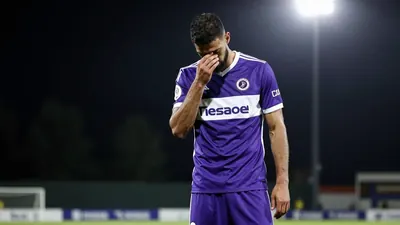 A 30-year-old Toulouse Football Club player, with a muscular build, wearing a purple and white jersey, looking dejected...