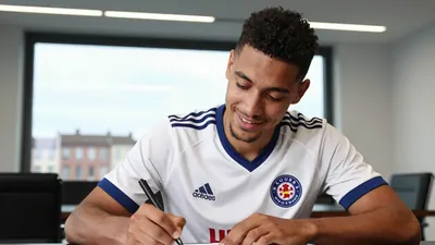 A close-up shot of an anonymous Danish midfielder in his mid-20s, wearing a white and blue jersey, with a black and white...